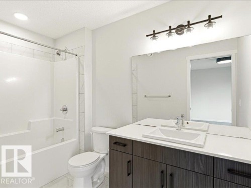 Contemporary bathroom featuring a dark wood-finish vanity with an integrated rectangular sink, white countertop, and a wall-mounted mirror - 17487 77 Street, Edmonton, AB - Indoor Photo Showing Bathroom