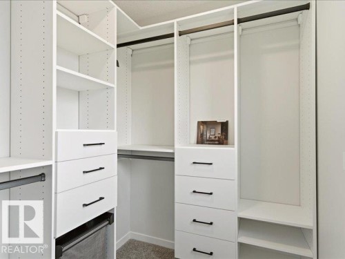 Custom closet system featuring white cabinetry, multiple shelves, integrated drawers with dark hardware, and hanging rods - 17487 77 Street, Edmonton, AB - Indoor With Storage