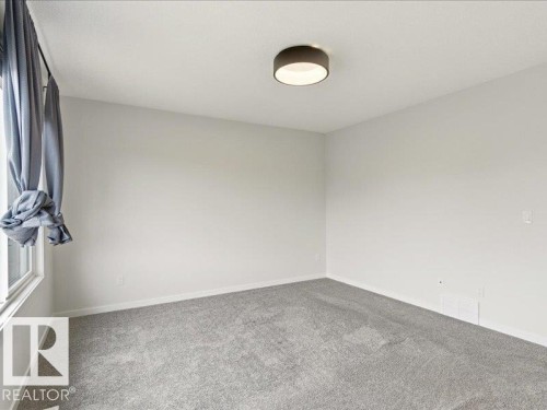 Neutral wall color in a room featuring gray carpet, a contemporary flush-mount ceiling light, and a window with trim - 17487 77 Street, Edmonton, AB - Indoor Photo Showing Other Room
