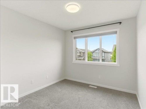 Room with light grey carpeting, white walls, and a large window featuring white trim - 17487 77 Street, Edmonton, AB - Indoor Photo Showing Other Room