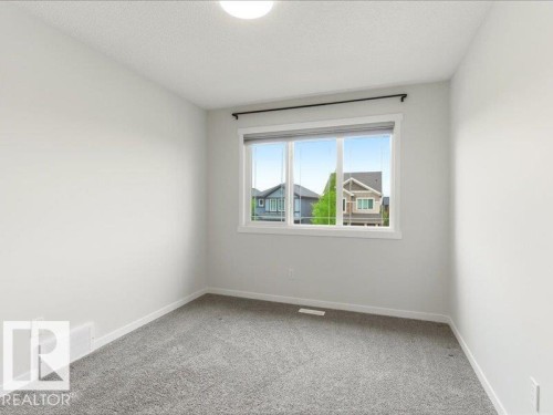 Interior room featuring a large window, gray carpeting, neutral wall paint, and a ceiling-mounted light fixture - 17487 77 Street, Edmonton, AB - Indoor Photo Showing Other Room