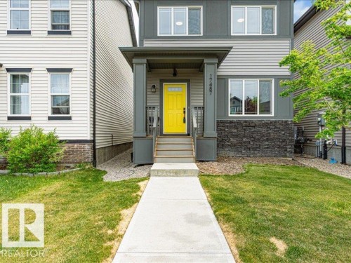 Contemporary exterior featuring dark grey siding, stone-look lower facade, and a bright yellow entry door - 17487 77 Street, Edmonton, AB - Outdoor With Facade