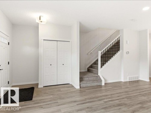 Entryway featuring wood-finish flooring, a contemporary ceiling light fixture, a paneled front door with upper glass inserts, and a bifold closet - 17487 77 Street, Edmonton, AB - Indoor Photo Showing Other Room