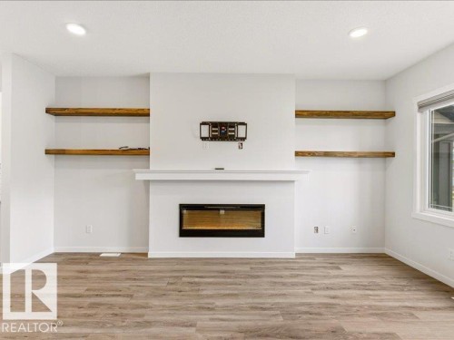 Living area featuring an electric fireplace with mantel, recessed shelving, wood-finish flooring, and recessed lighting - 17487 77 Street, Edmonton, AB - Indoor With Fireplace