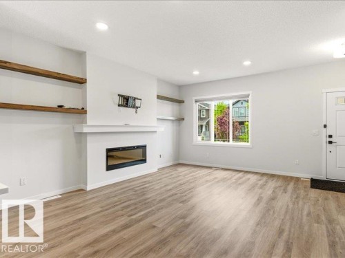 Open concept living space featuring wood-finish flooring, a contemporary linear fireplace, and recessed ceiling lighting - 17487 77 Street, Edmonton, AB - Indoor Photo Showing Living Room With Fireplace