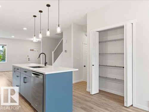 Kitchen island featuring a blue base, white countertop, integrated sink with a matte black faucet, and a stainless steel dishwasher - 17487 77 Street, Edmonton, AB - Indoor Photo Showing Kitchen With Upgraded Kitchen