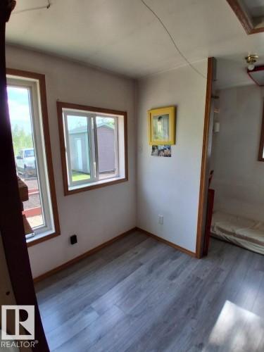 Interior space featuring wood-finish flooring, two windows with wood trim, and white walls - 204 Sandy Beach Way, Rural Two Hills County, AB - Indoor Photo Showing Other Room
