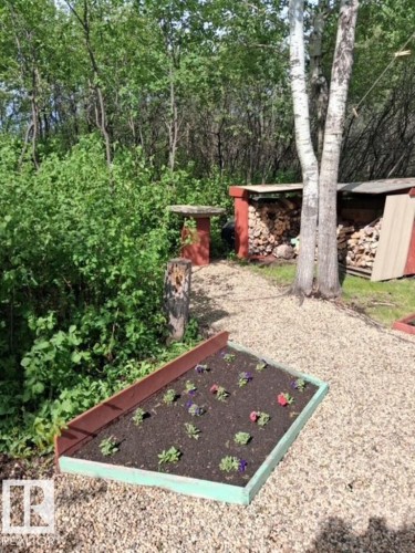 Raised garden bed with colorful plantings, set on a gravel path - 204 Sandy Beach Way, Rural Two Hills County, AB - Outdoor