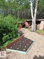 Raised garden bed with colorful plantings, set on a gravel path - 