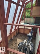 Wood-framed outdoor structure featuring a gravel floor, slatted wood sides, and a translucent roof - 