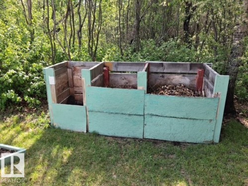 Three-bin compost system featuring painted wood construction, integrated into a natural, treed setting - 204 Sandy Beach Way, Rural Two Hills County, AB - Outdoor