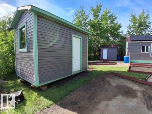 Gray horizontal siding with green trim and a white door - 204 Sandy Beach Way, Rural Two Hills County, AB - Outdoor With Exterior