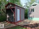 Gravel landscaping surrounding a gray utility building with a white entry door and a covered side storage area - 204 Sandy Beach Way, Rural Two Hills County, AB  - Outdoor With Exterior 