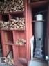 Built-in wood storage shelving alongside a compact wood-burning stove with metal flue - 204 Sandy Beach Way, Rural Two Hills County, AB  - Indoor Photo Showing Other Room 