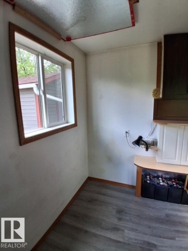 Room featuring a window with wood trim, wood-finish flooring, and a built-in cabinet with a countertop - 204 Sandy Beach Way, Rural Two Hills County, AB - Indoor Photo Showing Other Room