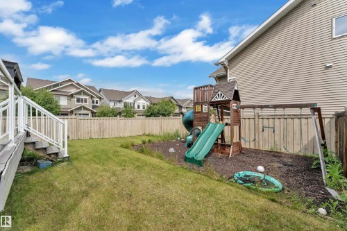 Expansive backyard featuring a lush lawn, privacy fencing, and a multi-level deck with white railings - 1942 Chapman Road Sw, Edmonton, AB - Outdoor