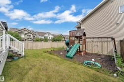 Expansive backyard featuring a lush lawn, privacy fencing, and a multi-level deck with white railings - 