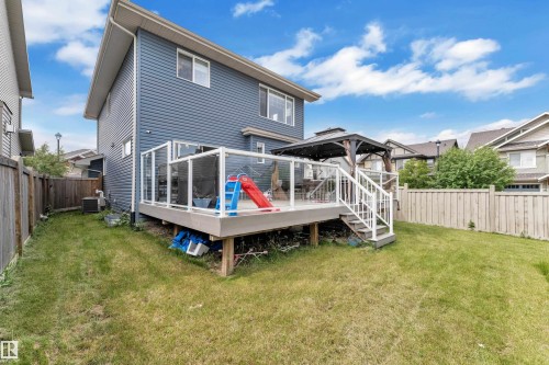 Expansive backyard featuring a raised deck with glass railings, a white staircase, and a dark gazebo - 1942 Chapman Road Sw, Edmonton, AB - Outdoor With Deck Patio Veranda With Exterior