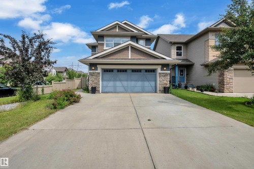 Two-story residence featuring a blue garage door and stone accents on the facade - 1942 Chapman Road Sw, Edmonton, AB - Outdoor With Facade