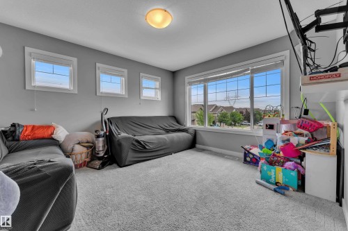 Carpeted room featuring multiple windows, a large fixed window overlooking residential structures, and three smaller rectangular windows - 1942 Chapman Road Sw, Edmonton, AB - Indoor