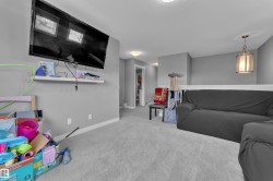 Carpeted loft area featuring a mounted television, a floating wall shelf, and a partial balustrade - 