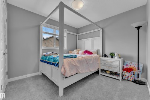 Carpeted bedroom with a window, light gray walls, and a ceiling-mounted light fixture - 1942 Chapman Road Sw, Edmonton, AB - Indoor Photo Showing Bedroom