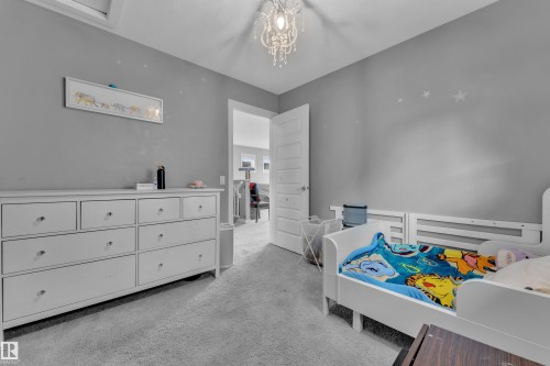 Carpeted room featuring a crystal chandelier and light gray walls - 1942 Chapman Road Sw, Edmonton, AB - Indoor Photo Showing Bedroom