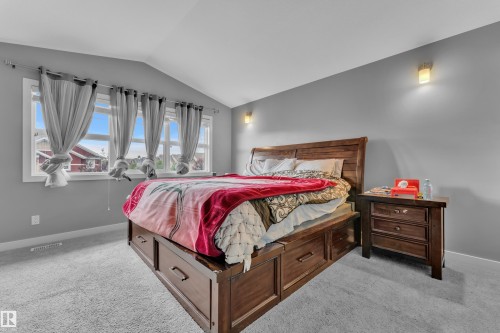 Bedroom featuring vaulted ceiling, multiple windows, wall-mounted light fixtures, and light-toned carpeting - 1942 Chapman Road Sw, Edmonton, AB - Indoor Photo Showing Bedroom
