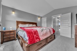 Vaulted ceiling bedroom featuring wall-mounted sconces, wood-finish bed frame with built-in storage drawers, and gray wall paint - 