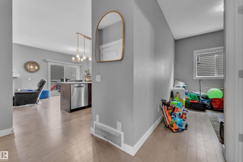 Open-concept living area featuring light wood-finish flooring, a contemporary island with a built-in dishwasher, and a multi-pendant light fixture - 1942 Chapman Road Sw, Edmonton, AB - Indoor Photo Showing Other Room