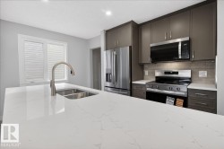 Kitchen featuring a large central island with a double stainless steel sink and a gooseneck faucet - 