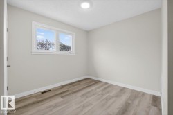 Bright room featuring a two-pane window, wood-finish flooring, light gray walls, white baseboards, and a flush-mounted ceiling light fixture - 