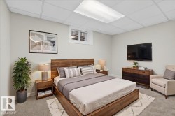 Bedroom featuring wood-finish flooring, a contemporary drop ceiling with integrated lighting, and a window providing natural light - 