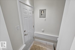Entryway featuring a paneled door with brushed nickel hardware, wood-finish flooring, and a white electrical panel - 