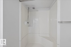 White fiberglass shower enclosure with an integrated seat and a handheld showerhead - 