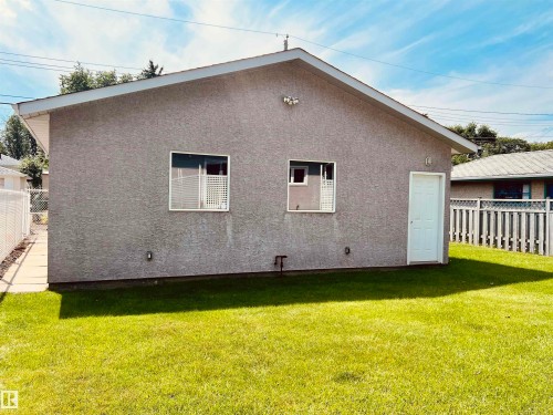 Exterior featuring a stucco finish, a pitched roof, and a white entry door - 9723 65 Avenue Nw, Edmonton, AB - Outdoor With Exterior