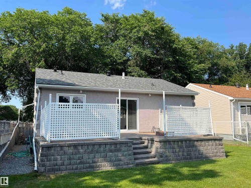 Private outdoor patio featuring a privacy lattice, block retaining wall, and a staircase to the yard - 9723 65 Avenue Nw, Edmonton, AB - Outdoor With Deck Patio Veranda