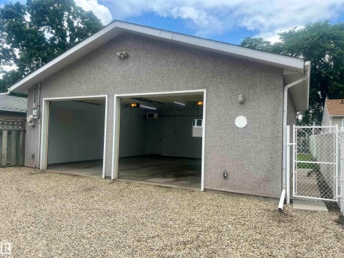 Two-car garage with a textured stucco exterior and a gravel driveway - 9723 65 Avenue Nw, Edmonton, AB - Outdoor With Exterior