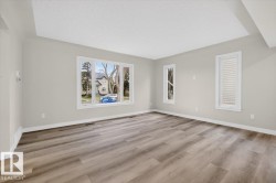 Spacious room featuring light-toned walls and wood-finish flooring - 