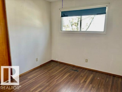Room featuring wood-finish flooring, white painted walls, a standard window with blinds, and a wood-panel closet door - 5206 51Ave, Willingdon, AB - Indoor Photo Showing Other Room