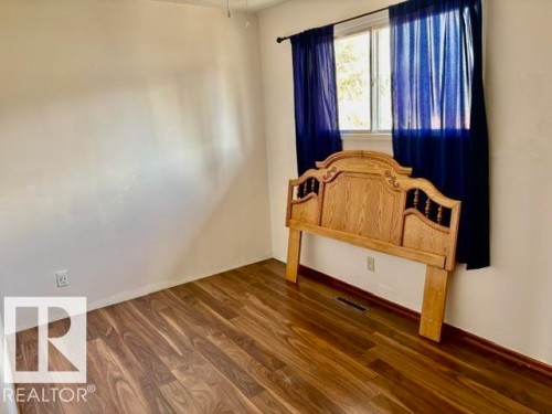 Bright room featuring wood-finish flooring, a window with a dark curtain rod, white walls, and white trim - 5206 51Ave, Willingdon, AB - Indoor Photo Showing Other Room