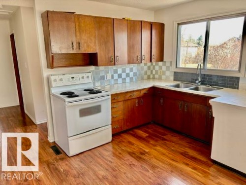 Kitchen featuring wood-finish flooring and ample cabinetry - 5206 51Ave, Willingdon, AB - Indoor Photo Showing Kitchen With Double Sink