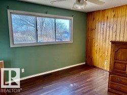 Interior room featuring wood-finish flooring and a wood paneled accent wall - 