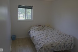 Bright room featuring a window with black blinds, light wood-finish flooring, and white painted walls - 