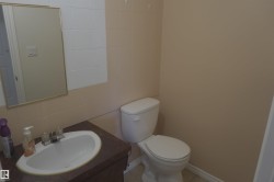Bathroom featuring a vanity with an integrated sink, a rectangular mirror, a toilet, and wall tiling - 