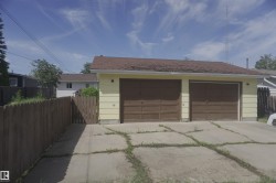 Detached two-car garage with yellow siding and brown garage doors - 