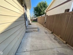 Concrete walkway featuring a wood fence and horizontal siding - 