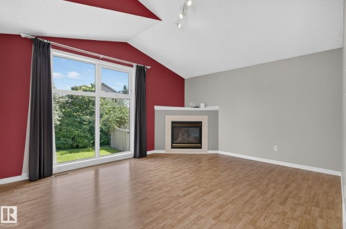 Living area featuring a vaulted ceiling and wood-finish flooring - 3211 Mcphadden Place Sw, Edmonton, AB - Indoor Photo Showing Living Room With Fireplace