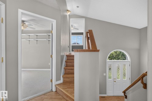 Vaulted ceiling entry featuring wood-finish flooring and a white arched front door with decorative glass inserts - 3211 Mcphadden Place Sw, Edmonton, AB - Indoor Photo Showing Other Room