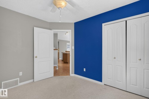 Carpeted room with a ceiling fan, bifold closet doors, and a doorway opening to a wood-finish floor area - 3211 Mcphadden Place Sw, Edmonton, AB - Indoor